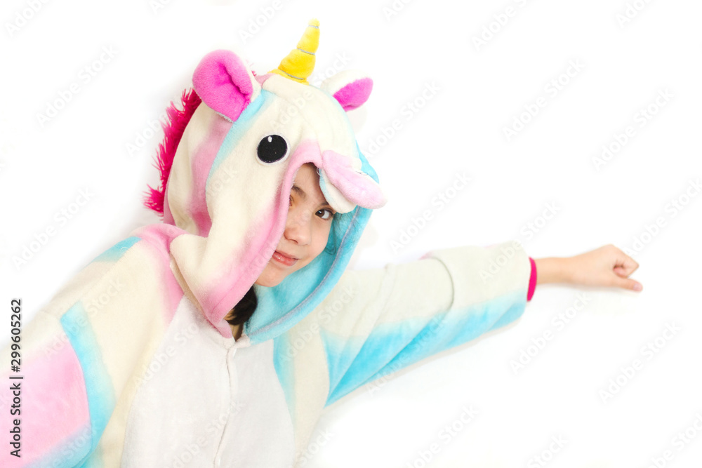 Positive young girl posing in funny pajamas. Girl in unicorn kigurumi isolated on white background - obrazy, fototapety, plakaty 