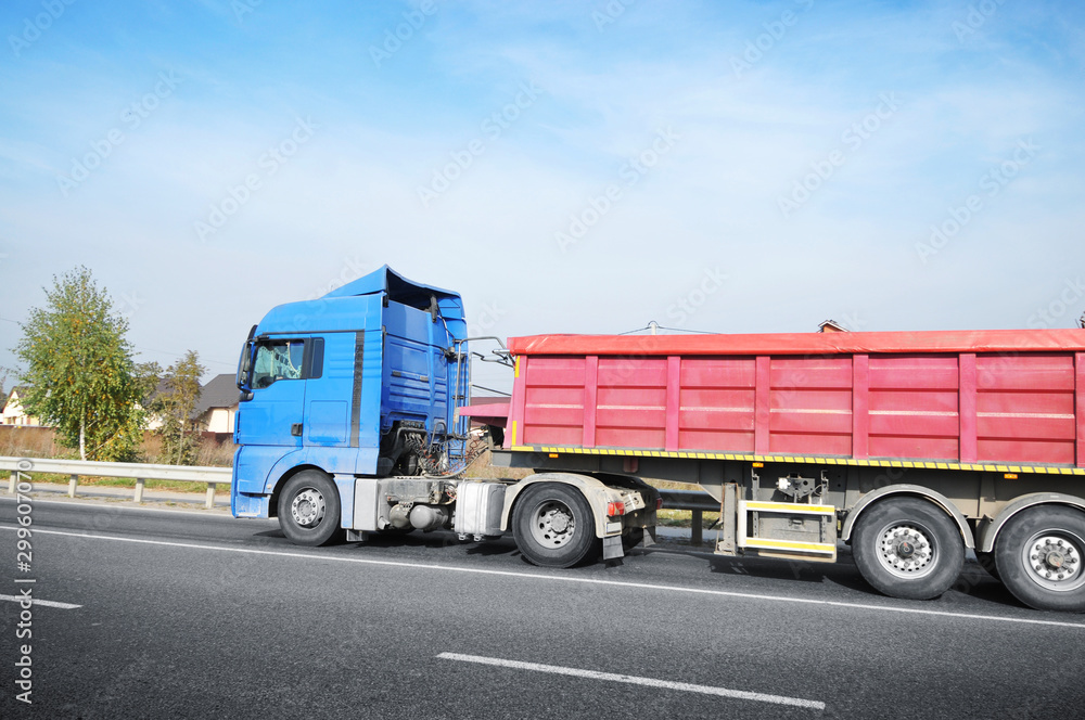 Truck with a trailer on the countryside road against blue sky with clouds Truck with a trailer on the countryside road against blue sky with clouds