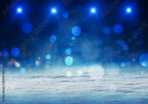 Winter abstract, blurred background with bokeh. Blurry night city lights in reflection on a snowy road. Neon light, falling snow, snowflakes.