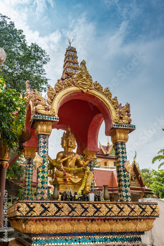 Ko Samui Island, Thailand - March 18, 2019: Wat Phra Yai Buddhist Temple on Ko Phan. Hindu 4-headed god Lord Brahma golden statue under eleborately decorated baldachin. Blue sky and green foliage.