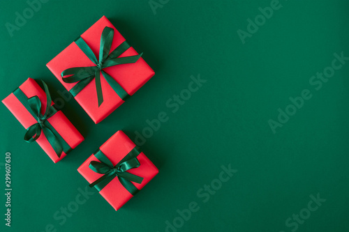 Red gift boxes on green background. Christmas card. Flat lay. Top view with space for text