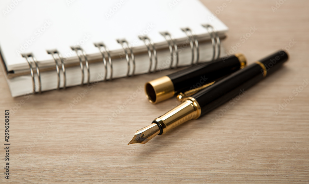 golden fountain pen near the notepad with paper closeup golden fountain pen near the notepad with paper closeup