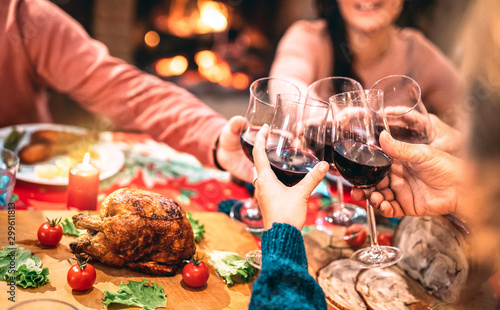 Family toasting red wine and having fun at Christmas supper party - Holiday celebration concept with happy people enjoying winter time together at home dinner fest - Warm filter with focus on glasses photo