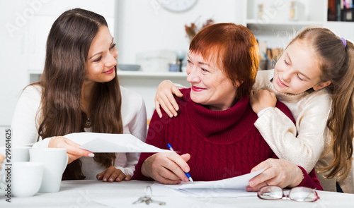 Smiling senior woman with family writing papers