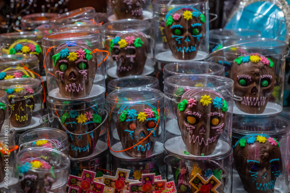 Fototapeta premium Chocolate and sequin skulls, typical sweets during the time of the day of the dead in Mexico, toy offerings made with crumbs and icing sugar