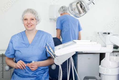 Dentist woman near dental chair, welcoming patient to office