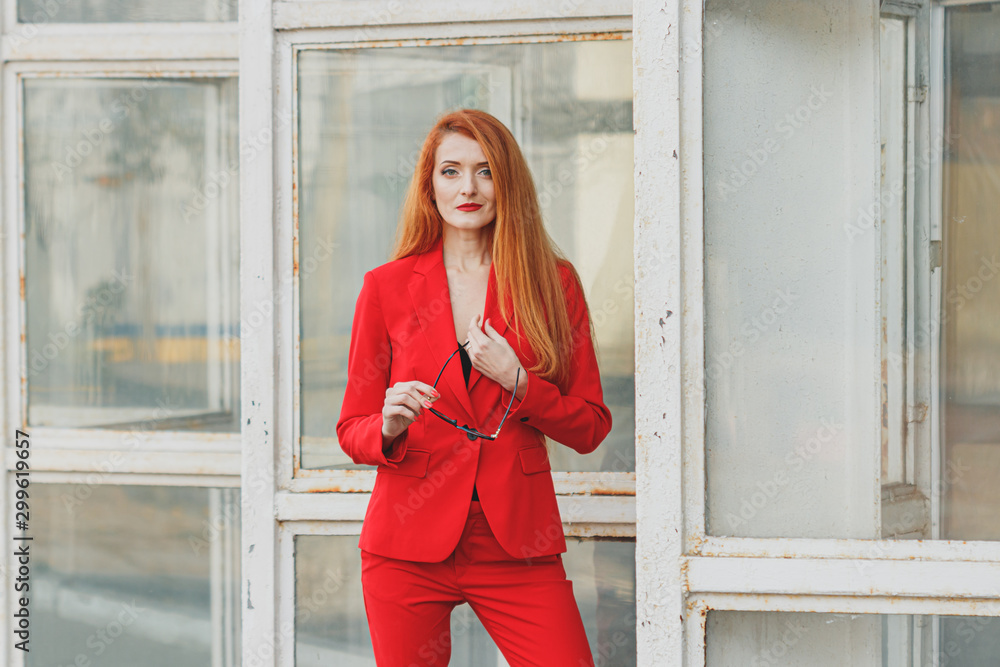 beautiful girl with red hair dressed in a red business suit. Business portrait. beautiful girl with red hair dressed in a red business suit. Business portrait.