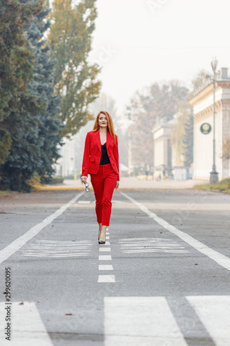 beautiful girl with red hair dressed in a red business suit. Business portrait.