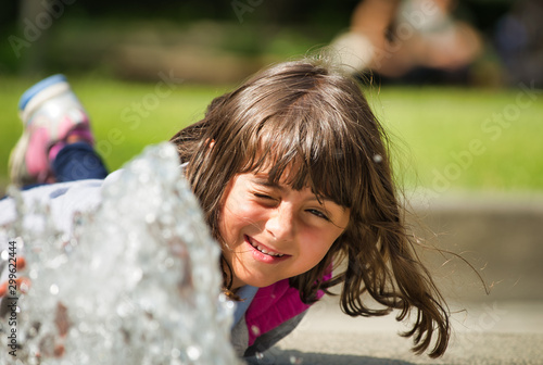 Happy face of a young girl playing with water in the park