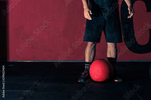 young athlete is ready to perform a medball lift in the gym for functional training, photography in a dark key, the concept of a healthy lifestyle and sports photo