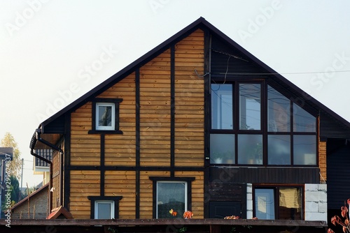 facade of a brown wooden house with windows against the sky © butus