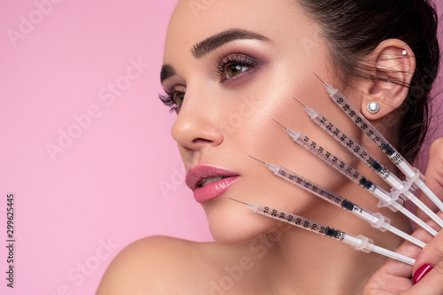 Cosmetology treatment on a brunette caucasian woman face. Fresh, clean skin with flawless features. She holds cosmetology items in her hands photo