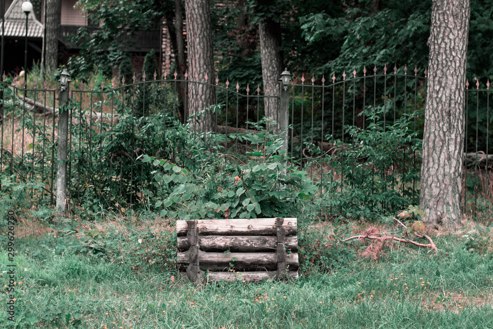 Wooden well in the forest. Wooden well and iron fence in the background Wooden well in the forest. Wooden well and iron fence in the background