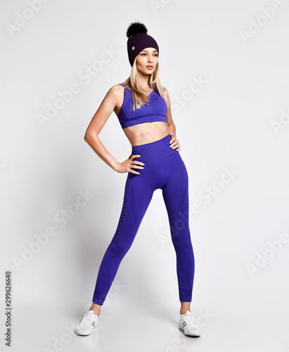 Sport girl working out standing in purple blue sportwear exercises on white background