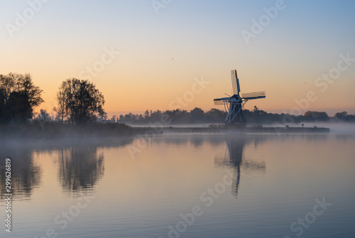 Nature awakens at a traditional Dutch windmill during a foggy sunrise. De Helper, Groningen.