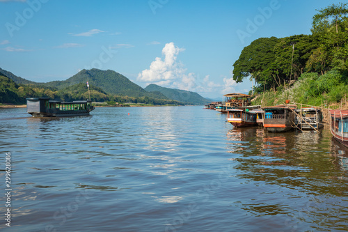 Traditional Long Boat on the Mekong River and mountains view in Luang Prabang, Laos.