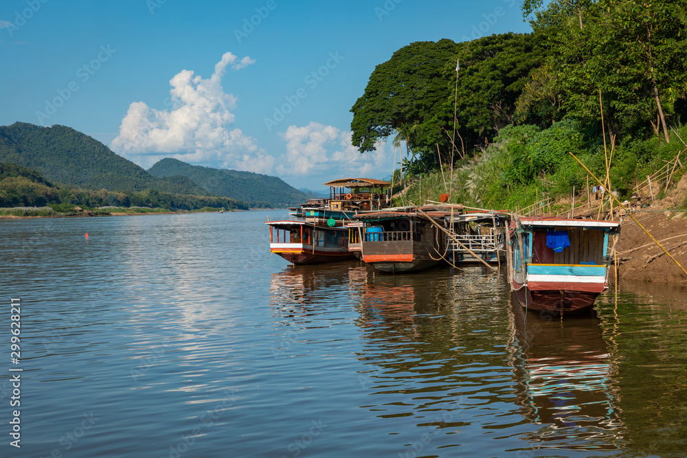 Traditional Long Boat on the Mekong River and mountains view in Luang Prabang, Laos. Traditional Long Boat on the Mekong River and mountains view in Luang Prabang, Laos.