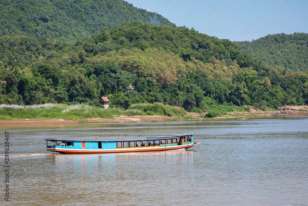 Obraz premium Traditional Long Boat on the Mekong River and mountains view in Luang Prabang, Laos.