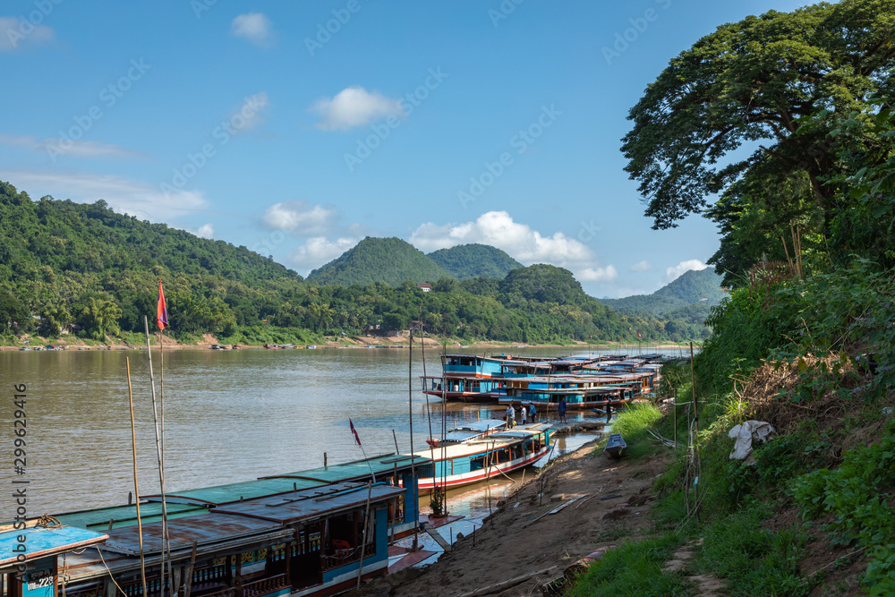 Fototapeta premium Traditional Long Boat on the Mekong River and mountains view in Luang Prabang, Laos.