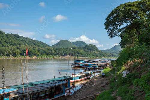 Traditional Long Boat on the Mekong River and mountains view in Luang Prabang, Laos. © Curioso.Photography
