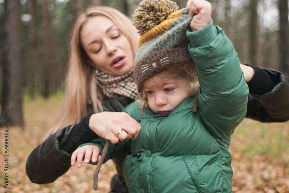 mom wears a hat to a child on the street. Portrait of cheerful little baby having fun with trendy mom outdoor mom wears a hat to a child on the street. Portrait of cheerful little baby having fun with trendy mom outdoor