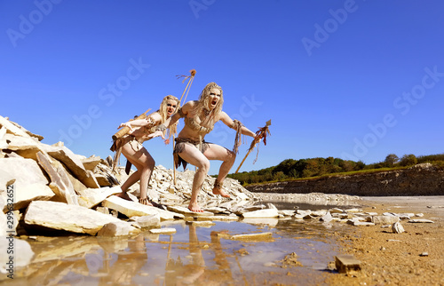 Two girls are dressed as neanderthal warriors. They are covered with mud,filth and dirt and are seen in a stone quarry.