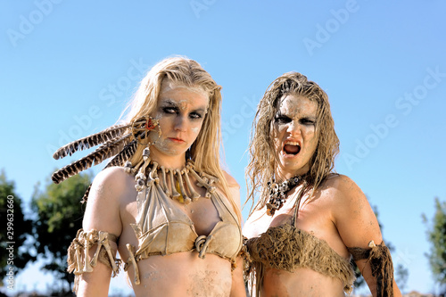 Two girls are dressed as neanderthal warriors. They are  covered with mud,filth and dirt and are seen in a stone quarry. photo