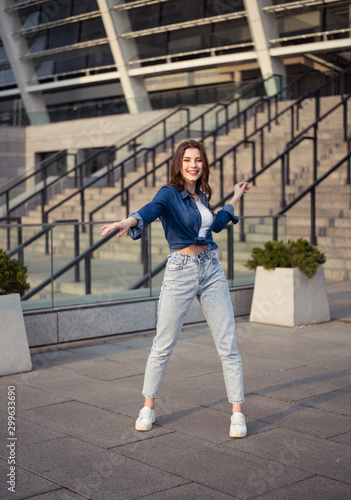 Portrait of european young beautiful smiling woman with dark straight hair in jeans shirt on cityscape background © Anastasia Rudenko