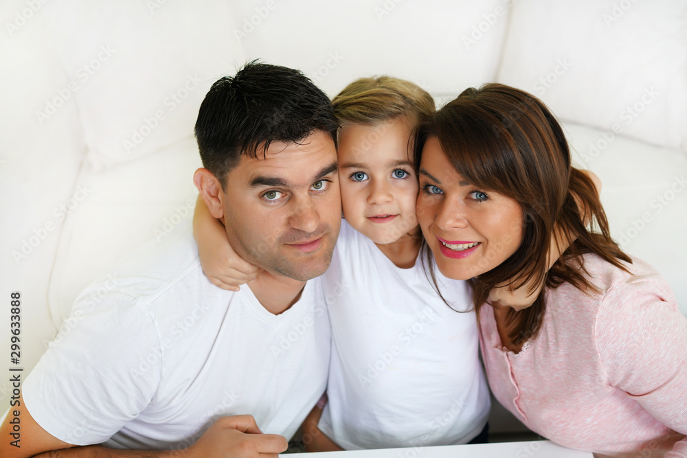 Big hug, mother, father and daughter together, looking at camera. Family theme Big hug, mother, father and daughter together, looking at camera. Family theme