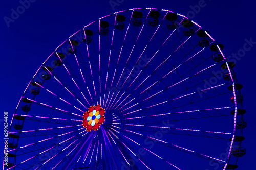 Colorful ferriswheel in vivid neon colors during evening with a dark blue sky