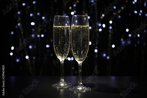 Champagne glasses against dark background with blurred lights, copy space