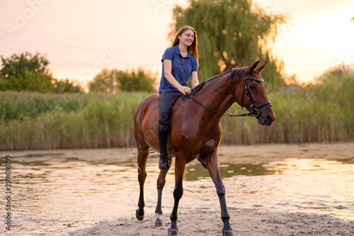A young girl riding a horse on a shallow lake. A horse runs on water at sunset. Care and walk with the horse. Strength and Beauty © Kate