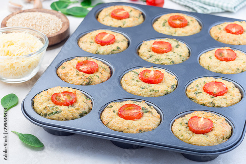 Savory muffins with quinoa, cheese and spinach topped with tomato, in  muffin tin, horizontal