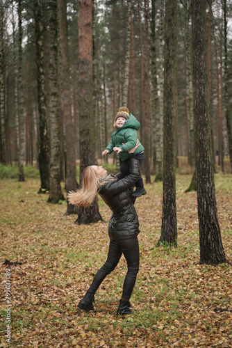 caucasian young mother and little child having fun in autumn Park, walking