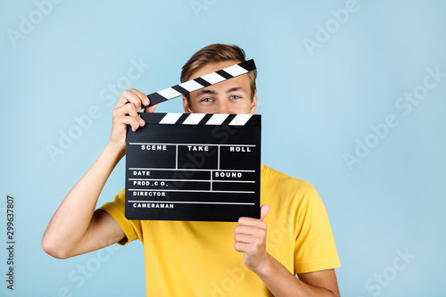 Obraz na płótnie Young man with clapper board on blue background