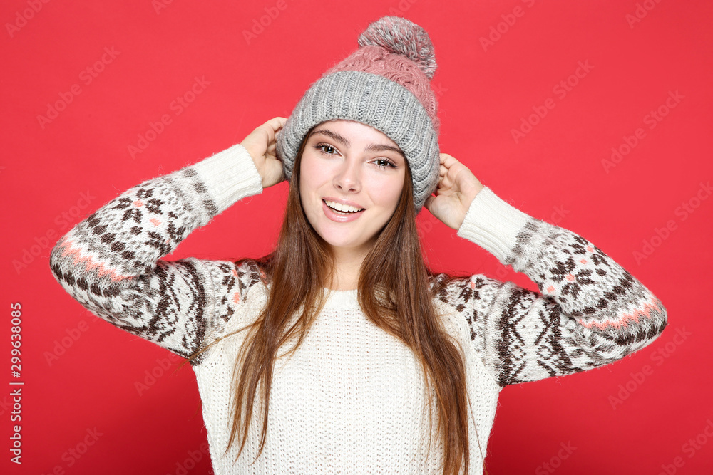 Beautiful woman in sweater and hat on red background Beautiful woman in sweater and hat on red background