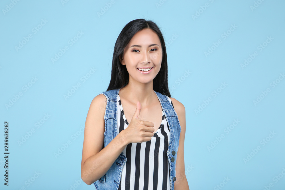 Beautiful young woman showing thumb up on blue background Beautiful young woman showing thumb up on blue background
