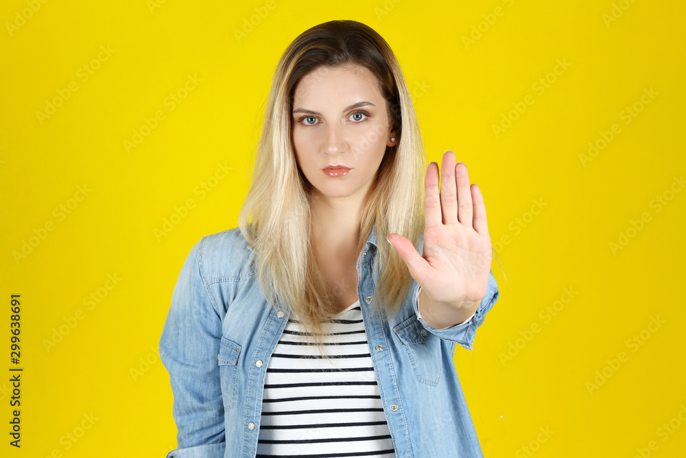 Young woman showing hand palm on yellow background Young woman showing hand palm on yellow background