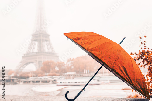 Fototapeta Naklejka Na Ścianę i Meble -  Bright orange umbrella on a rainy autumn foggy day in Paris against the background of the Eiffel tower