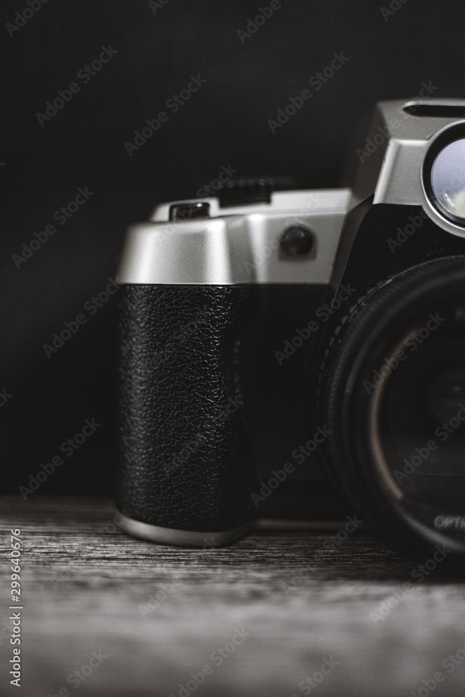 Silver and black analog camera over a wood texture and black background 