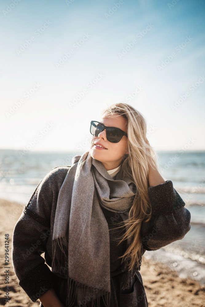 Spectacular attractive Scandinavian blonde on the shore of the Baltic Sea in autumn in a warm cozy cardigan coat Spectacular attractive Scandinavian blonde on the shore of the Baltic Sea in autumn in a warm cozy cardigan coat