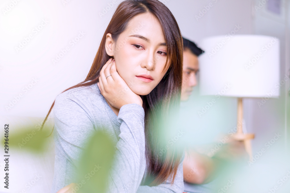Unhappy young woman sitting on sofa with boyfriend while stress not talking after fight in living room. Upset wife thinking with her husband sitting on sofa. Relationship problem lover concept. Unhappy young woman sitting on sofa with boyfriend while stress not talking after fight in living room. Upset wife thinking with her husband sitting on sofa. Relationship problem lover concept.