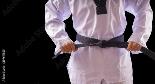 Taekwondo traditional man hand hold black-belt on black background for advertising. The karate man standing with black belt isolated on black with copy space.