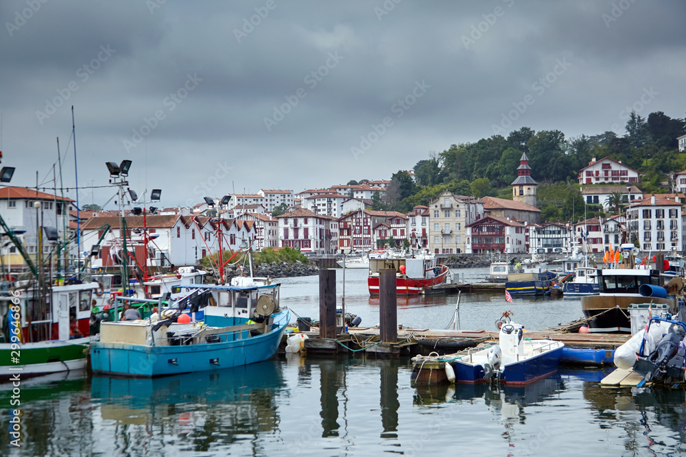 Boats moored in the fishing port of Saint-Jean-de-Luz / Ciboure (France). French Basque country. Coastal town on the shore of the Bay of Biscay in cloudy weather day with grey sky