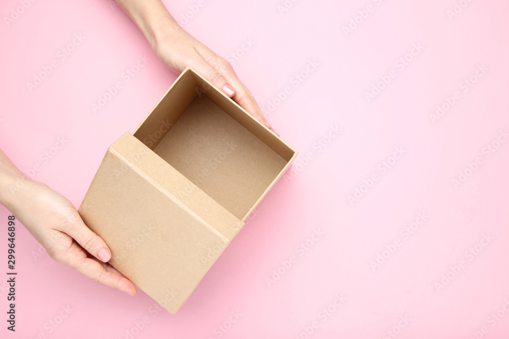 Female hands opening brown gift box on pink background - obrazy, fototapety, plakaty 
