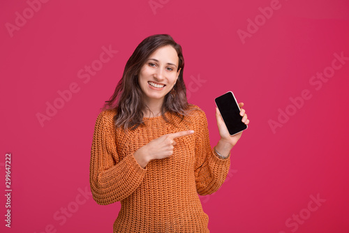 Happy young trendy woman pointing at smartphone screen