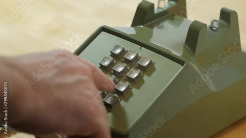 Man dialing retro push button rotary dial telephone. Making phone call on vintage avocado green landline phone.