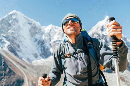 Fototapeta Naklejka Na Ścianę i Meble -  Portrait of smiling Hiker man on Taboche 6495m and Cholatse 6440m peaks background with trekking poles, UV protecting sunglasses. He enjoying mountain views during Everest Base Camp trekking route.