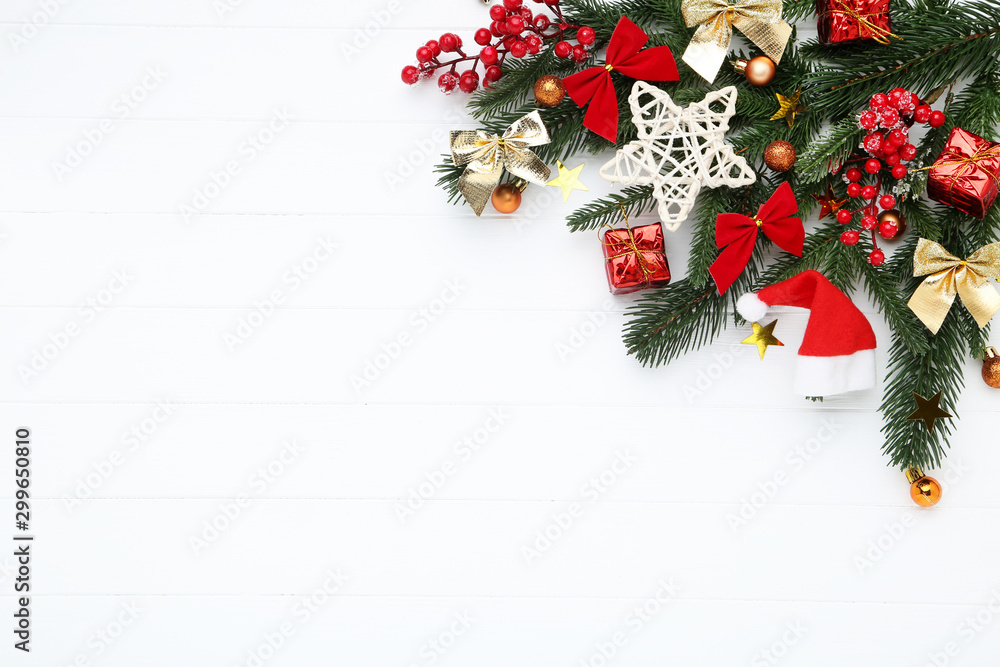 Christmas tree branches with toys and gift boxes on white wooden table