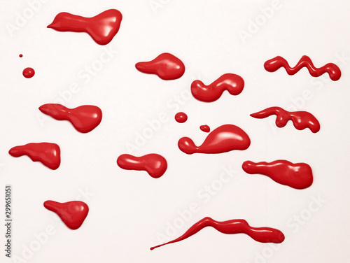A photograph of red paint blobs crawling on a white surface